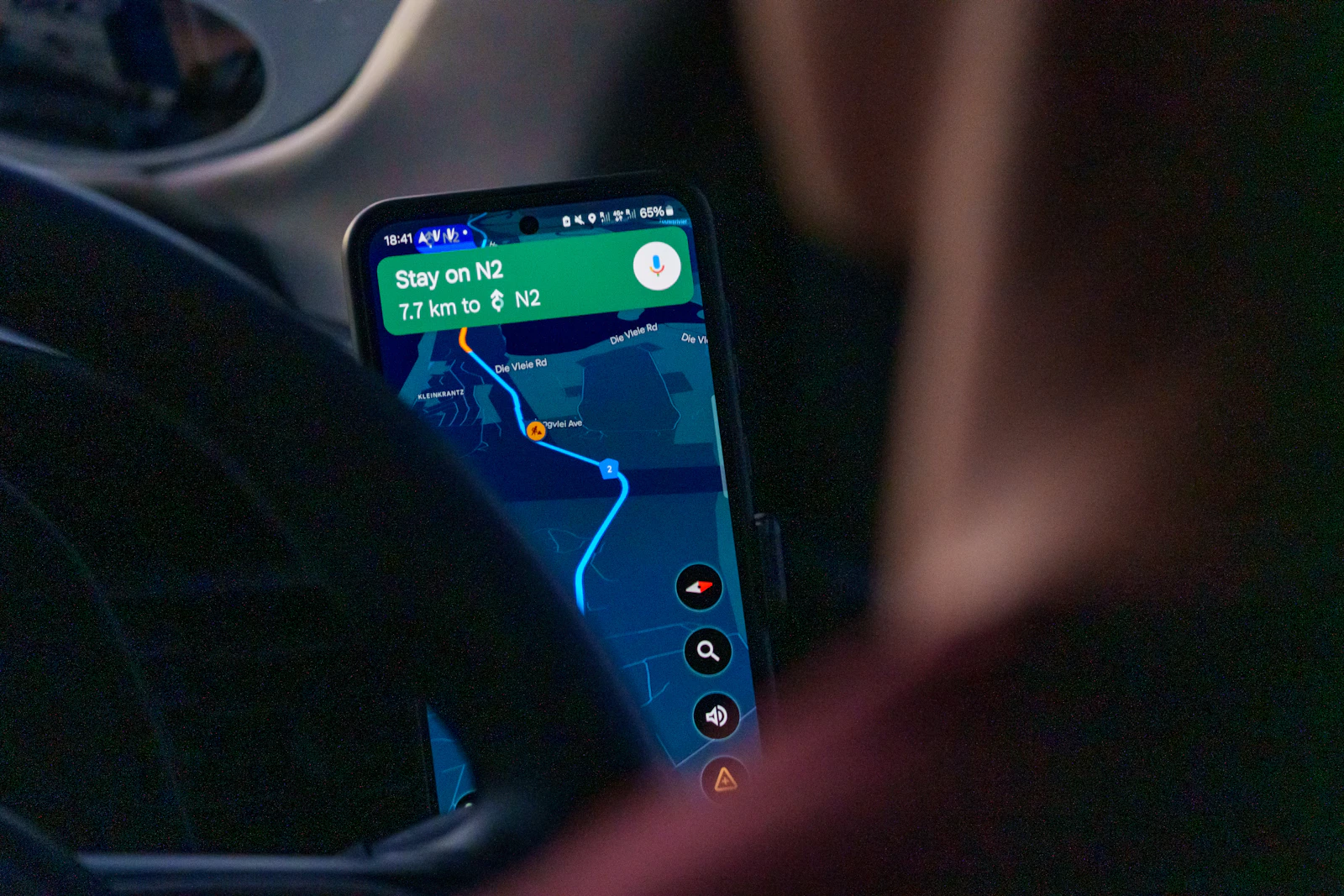 A driver using Google Maps navigation on a smartphone while behind the wheel of a car