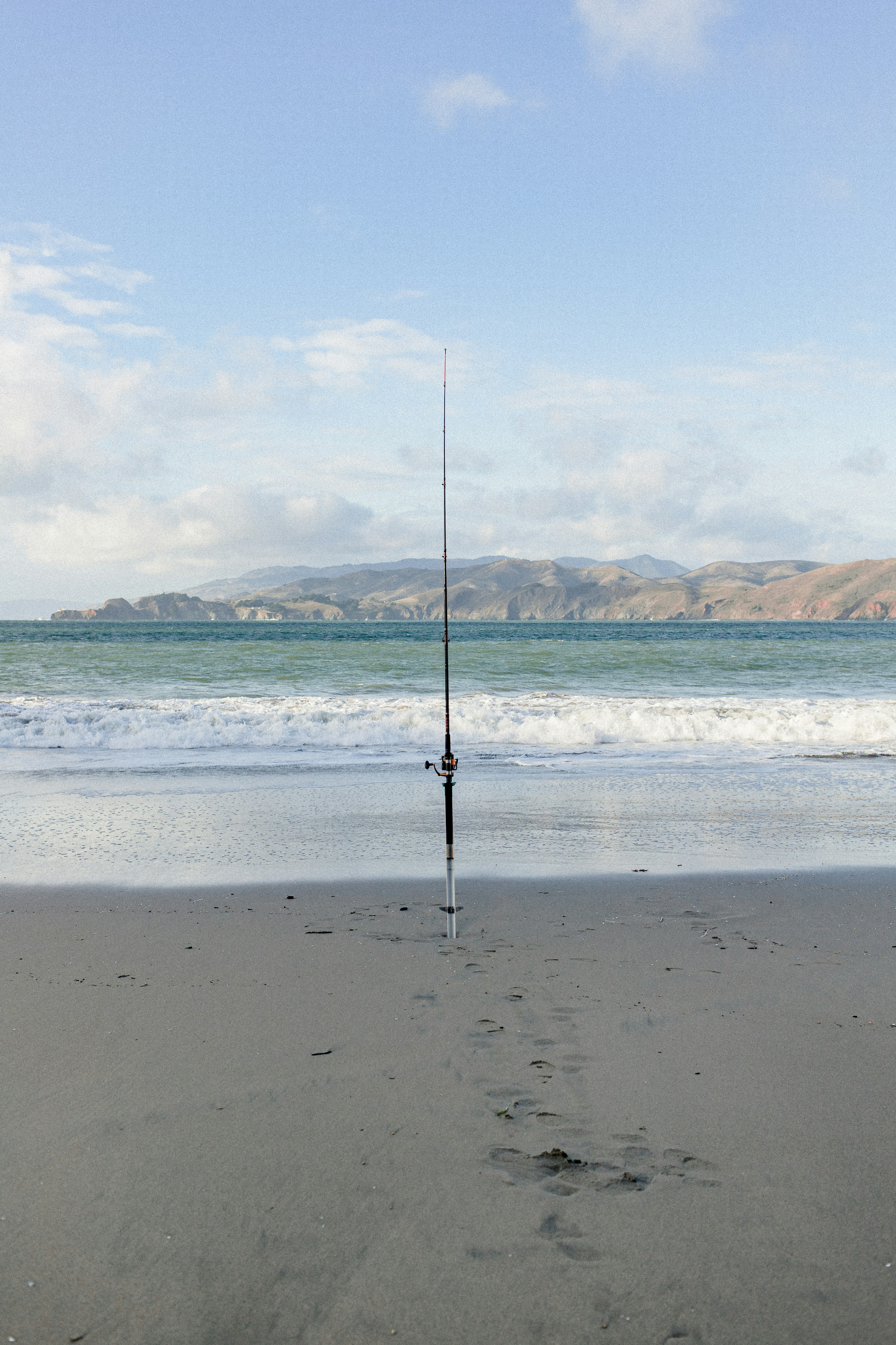 Fishing rod on beach with ocean and hills