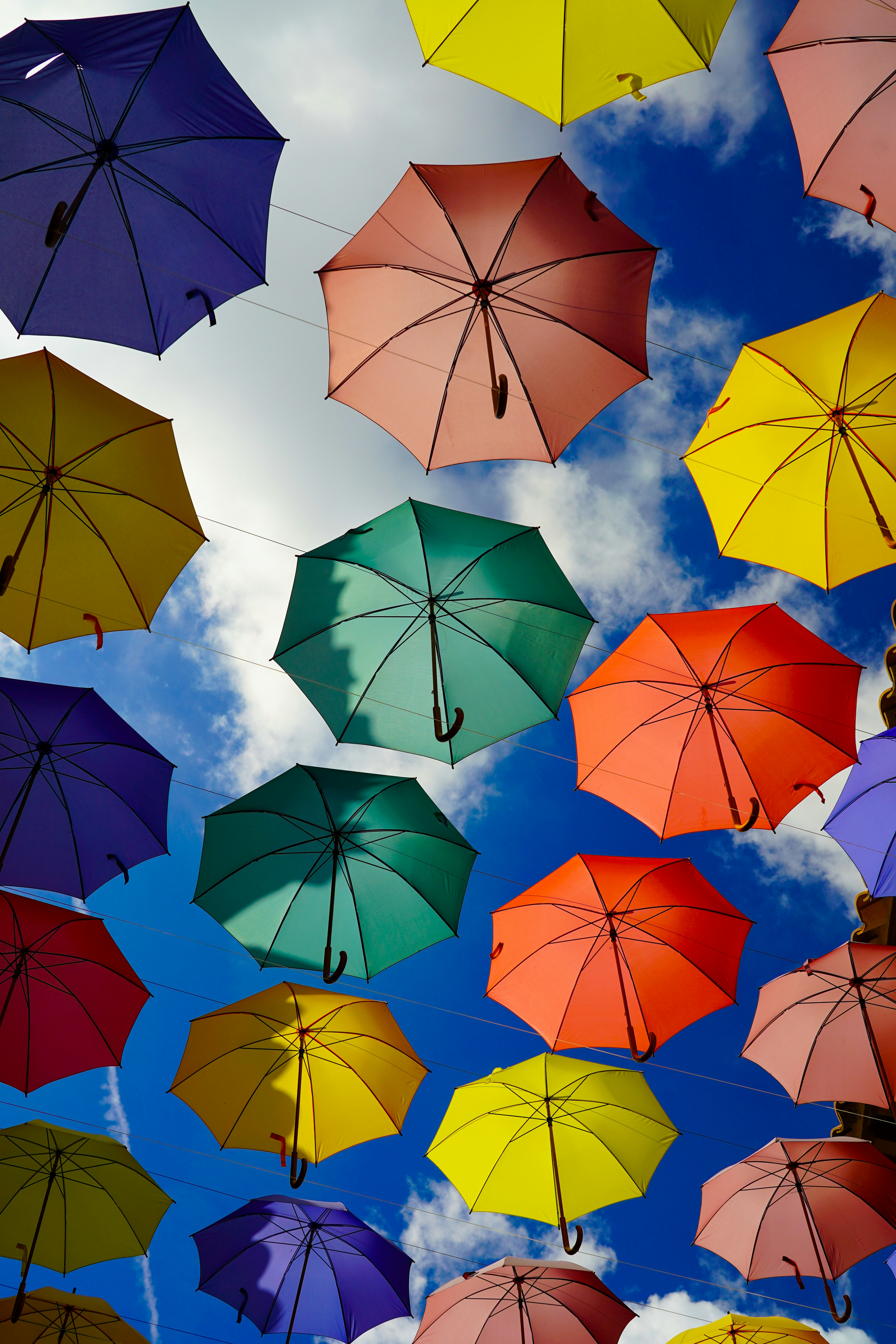 Colorful umbrellas suspended against a blue sky.
