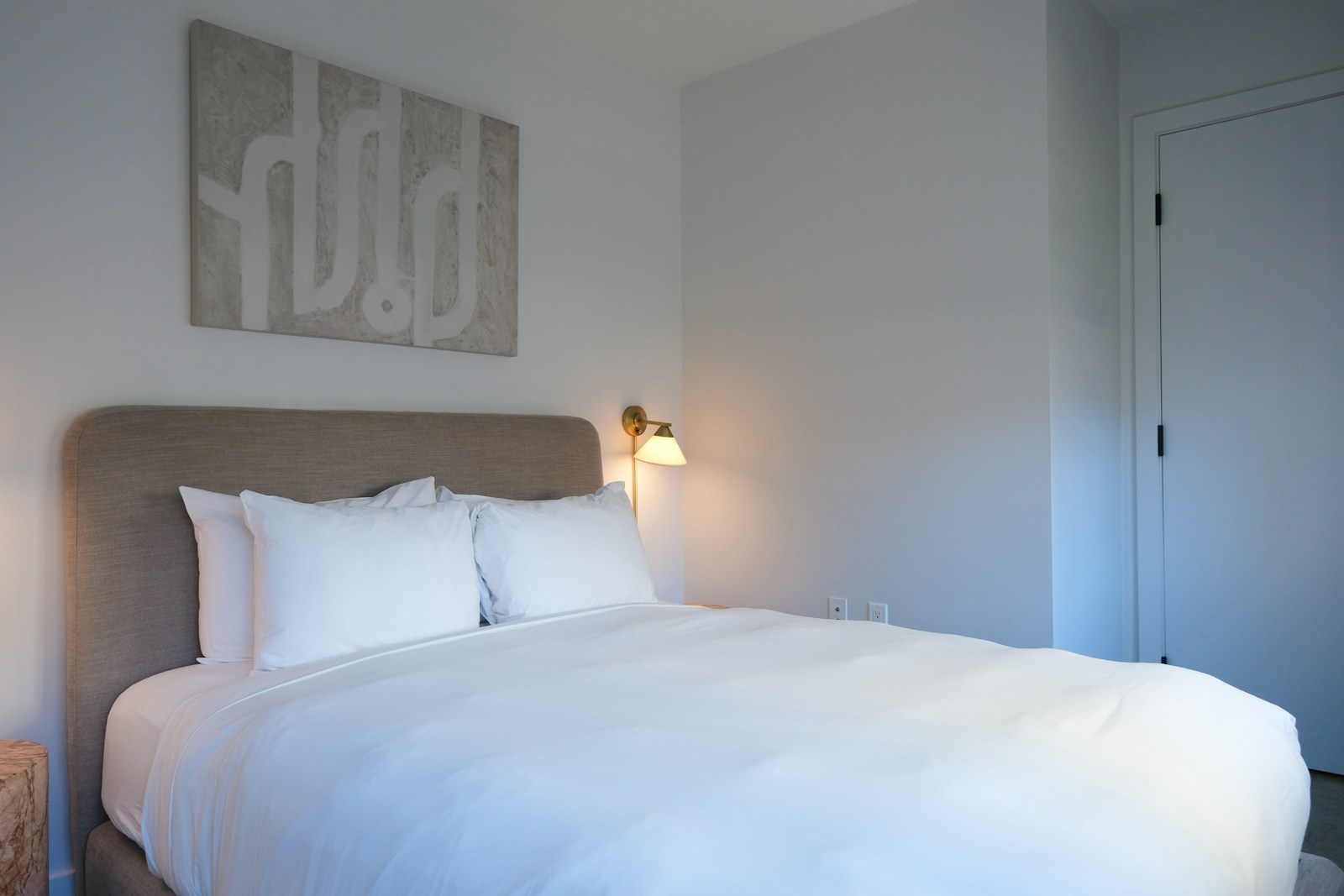 A neatly made hotel bed with crisp white linens and stacked pillows