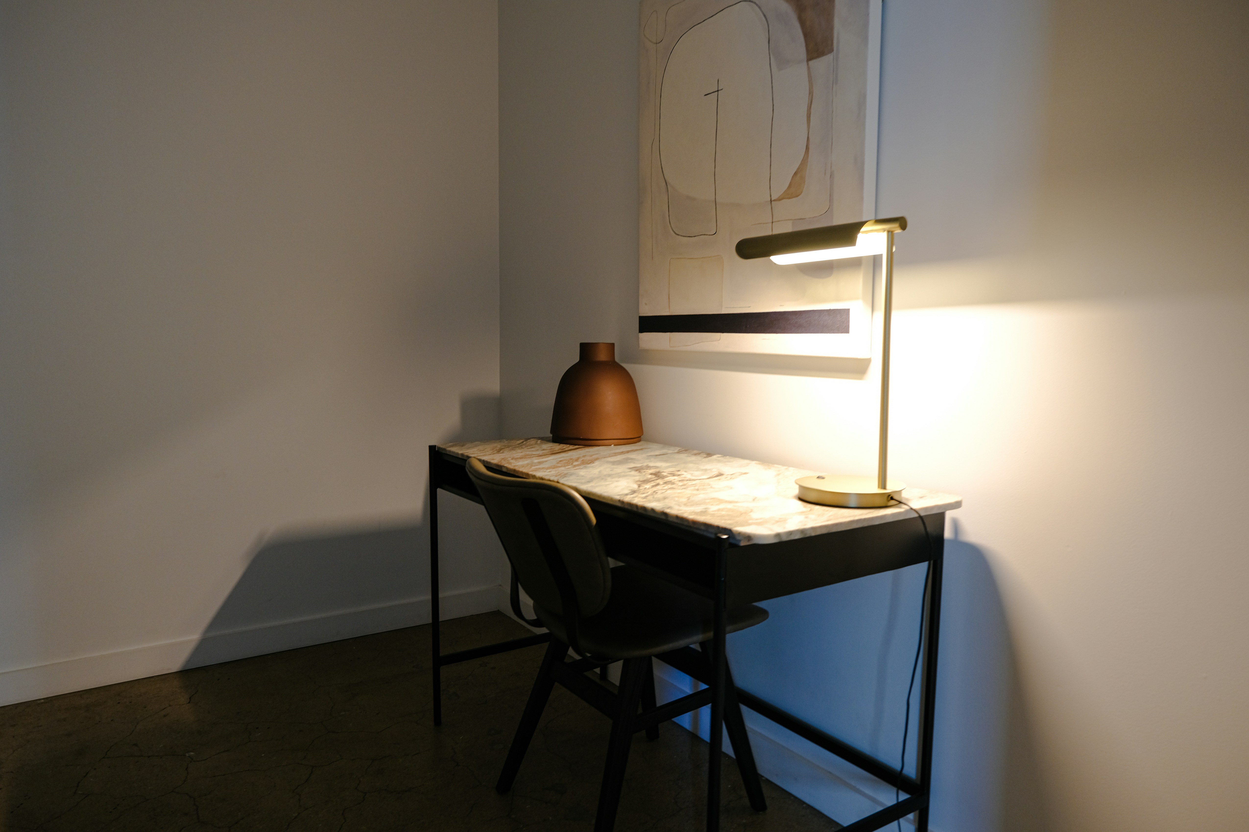 Desk with lamp, vase, and artwork