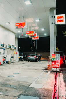 Cars at a brightly lit gas station at night