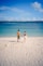 Couple holding hands walking on a sandy beach.
