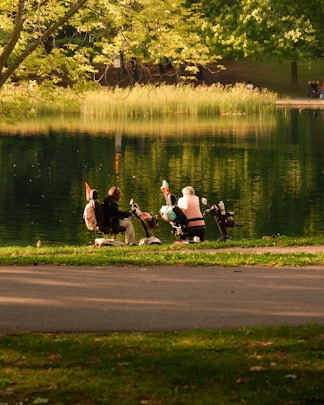 Two people on scooters by a lake.
