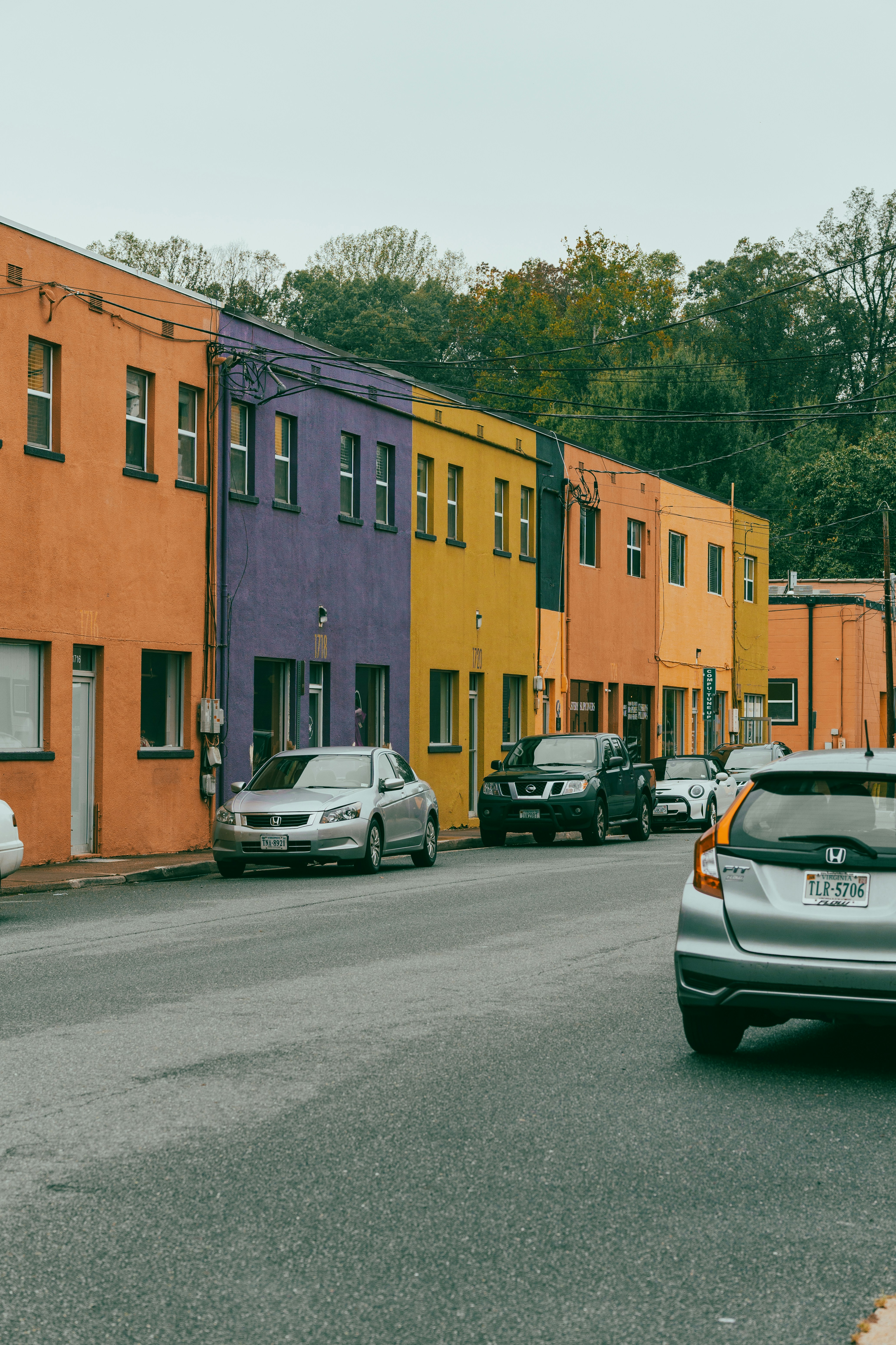 Colorful buildings line a street with parked cars.