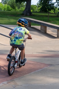 Boy in helmet rides bicycle at skate park.