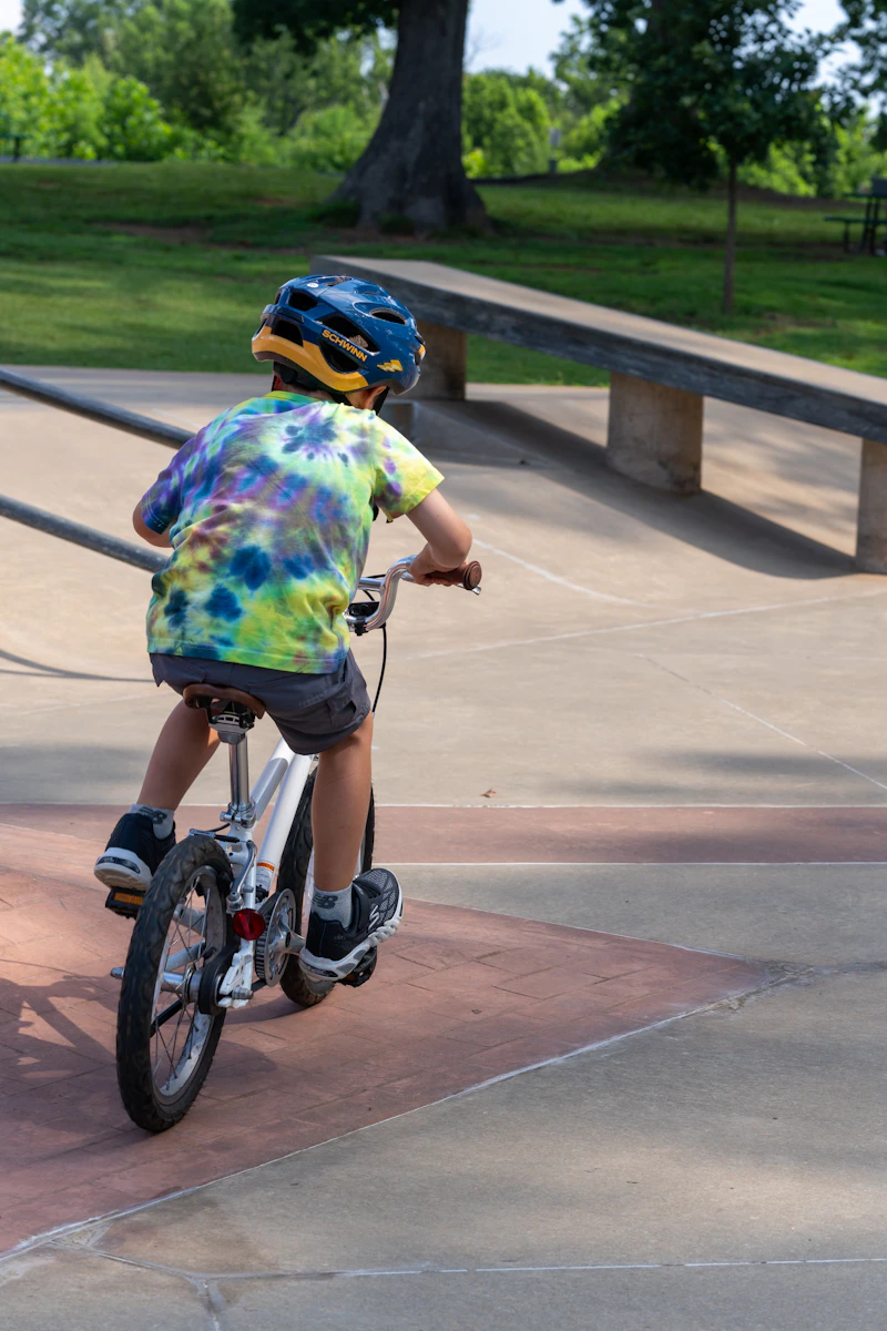 A young rider in a helmet riding the banked asphalt of a track.