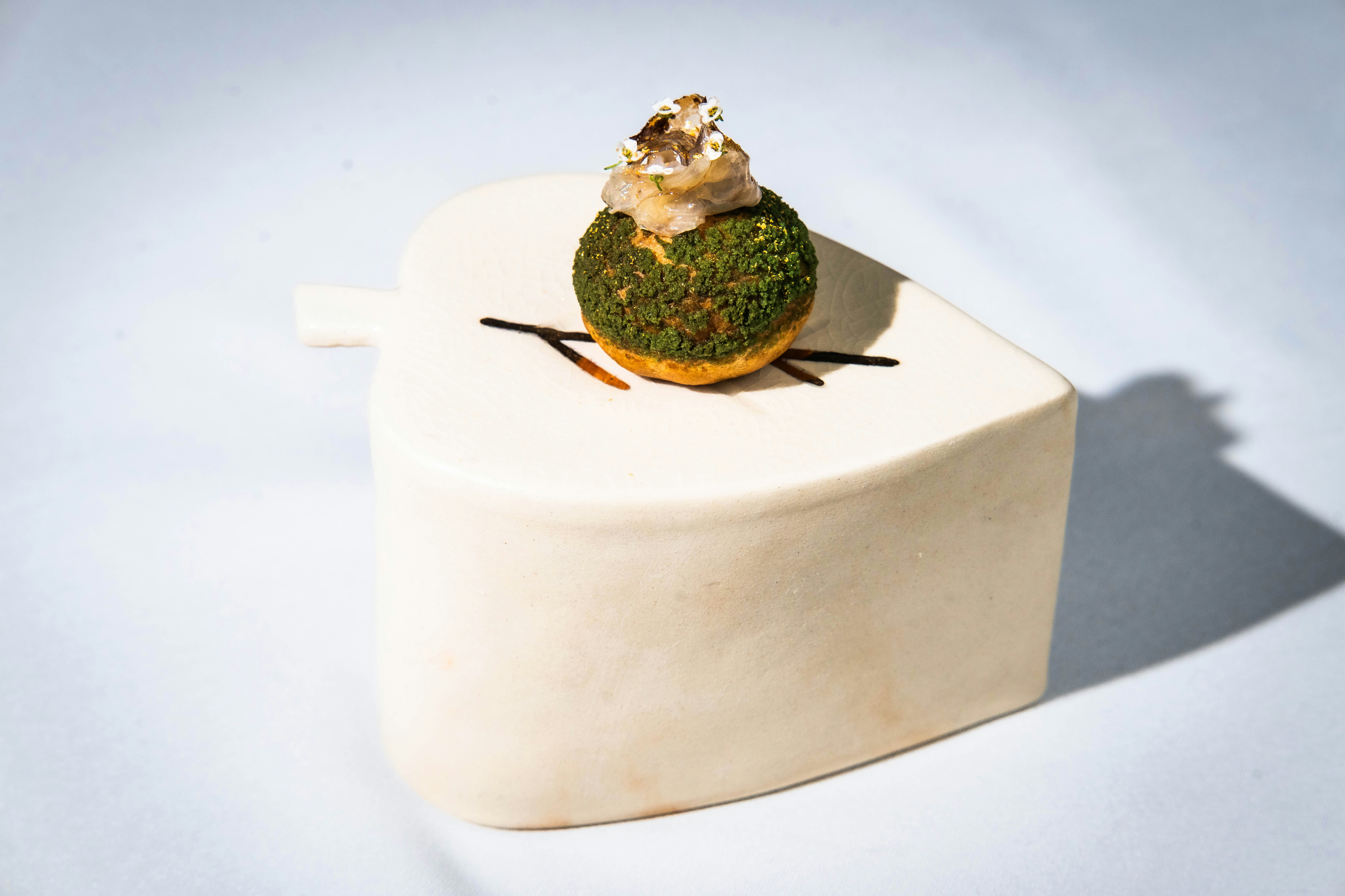 Gourmet dessert with green topping on white plate.