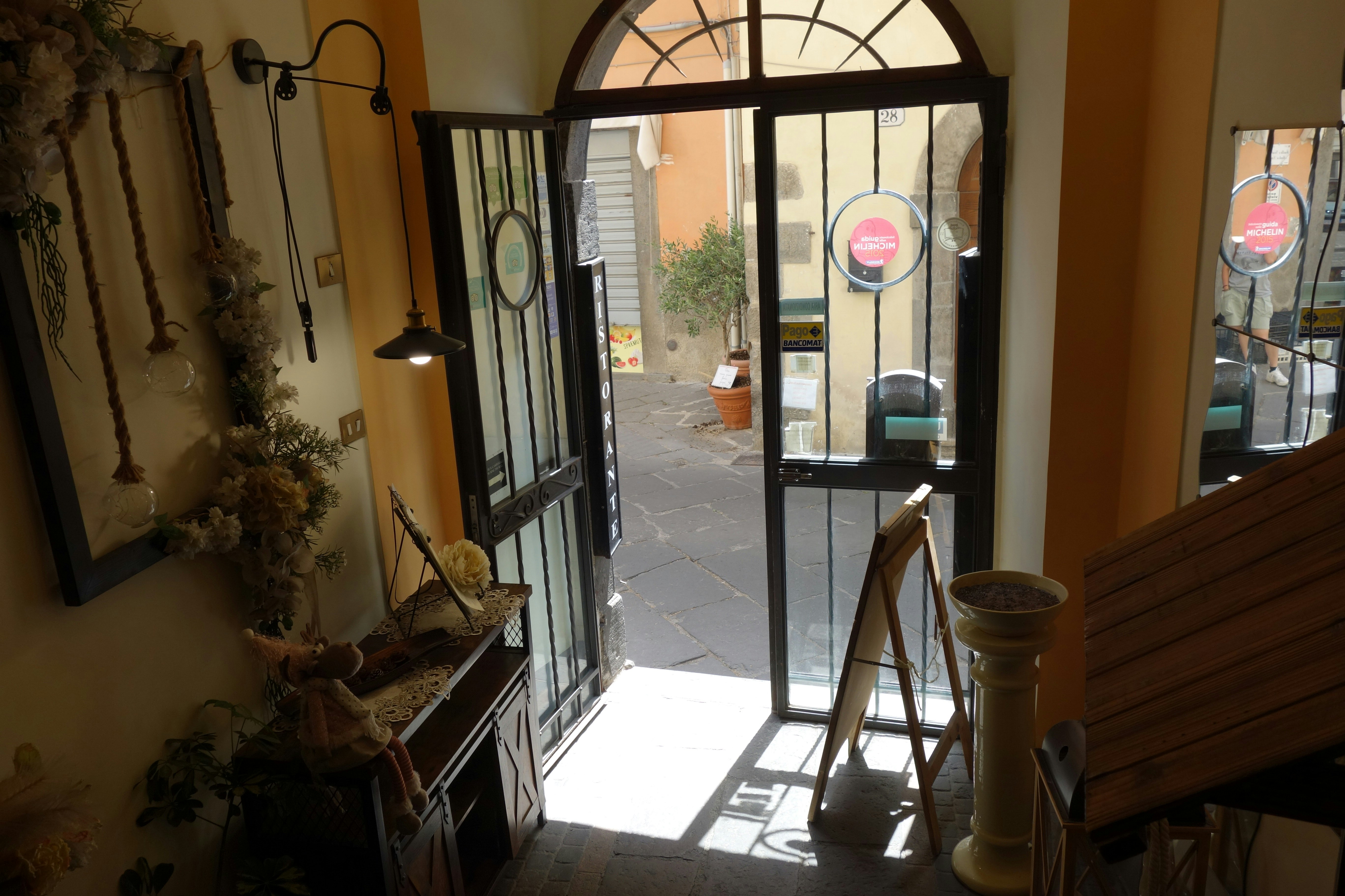 View through open doorway to a sunlit courtyard.