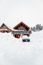 Modern house buried in deep snow with car.