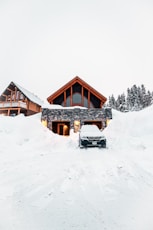Modern house buried in deep snow with car.
