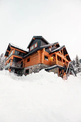 A large log cabin surrounded by deep snow.