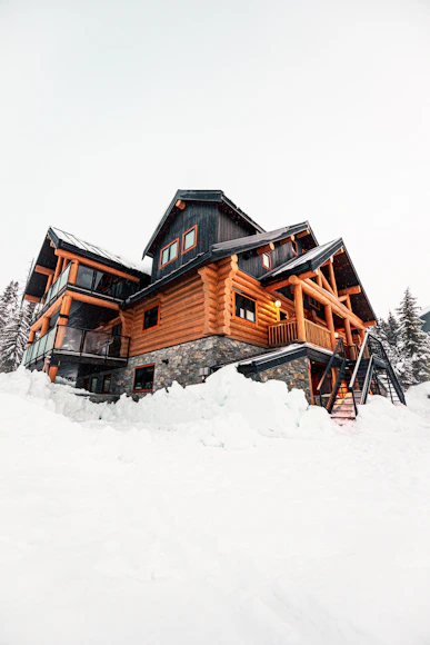 A large log cabin surrounded by deep snow.