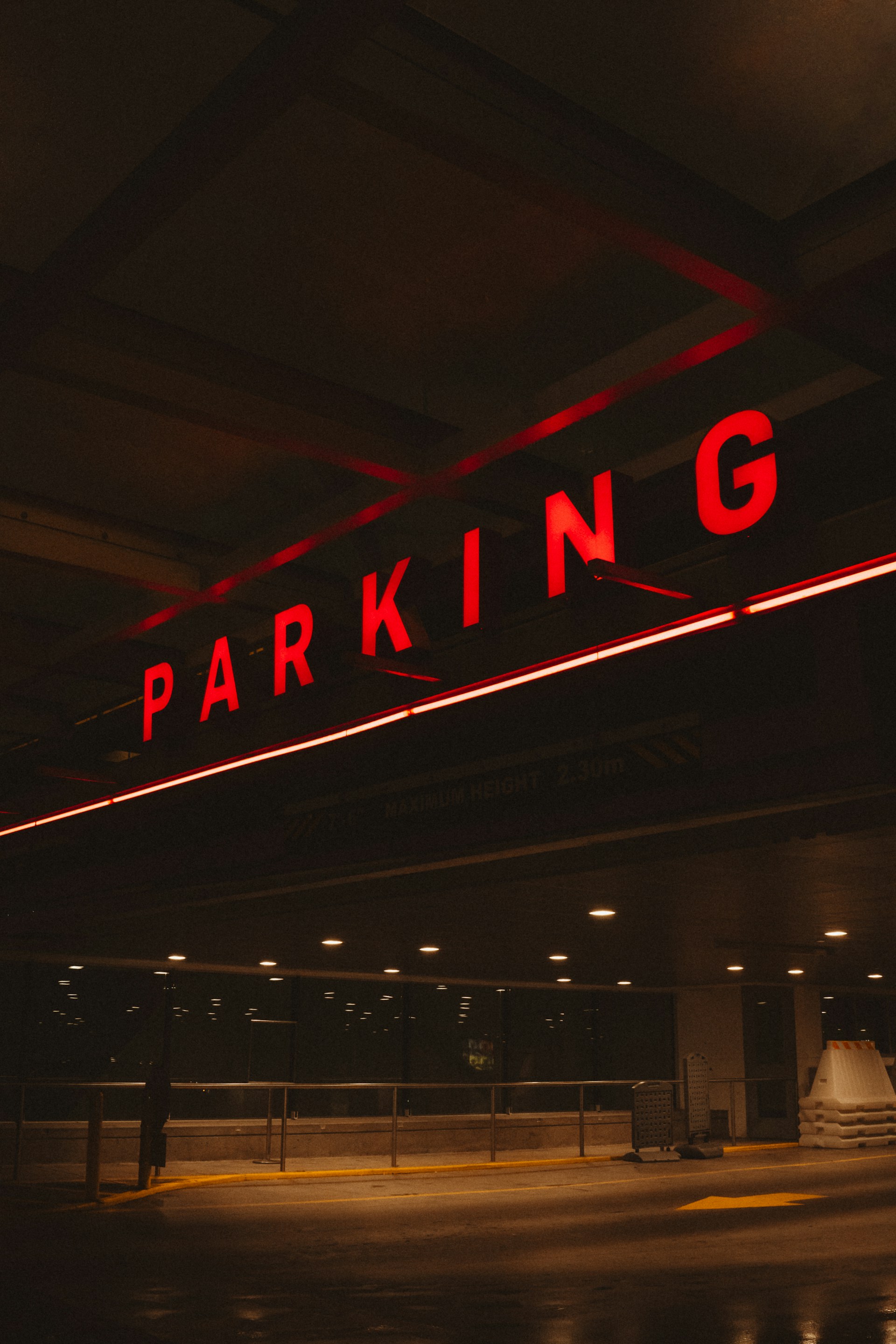 Bright red neon parking sign in a dark garage.