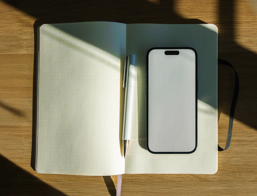 Notizbuch, Stift und Smartphone im Sonnenlicht auf einem Holztisch