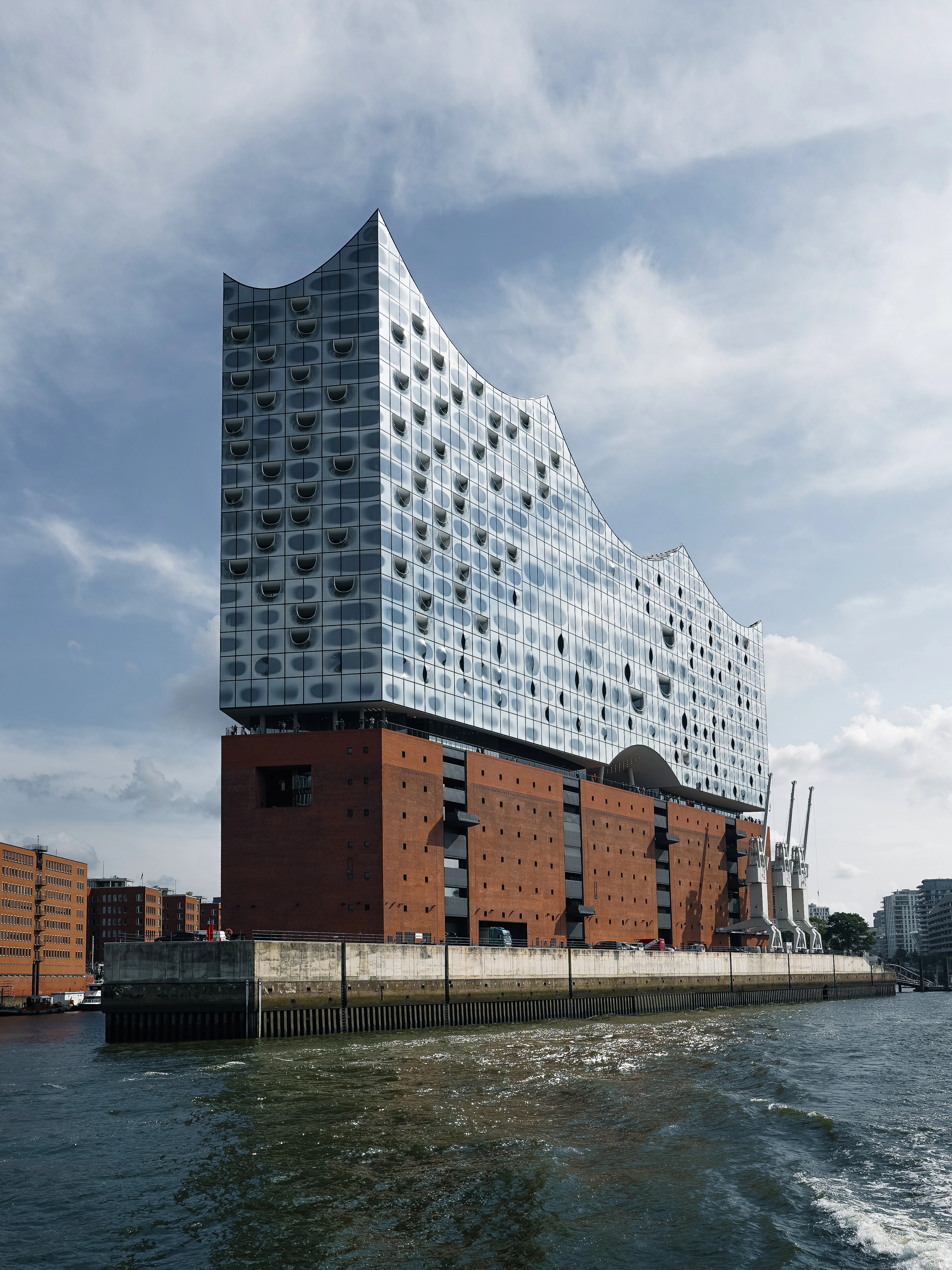 The glass wave-shaped crown of the Elbphilharmonie concert hall rising above its brick warehouse base on the Elbe in Hamburg