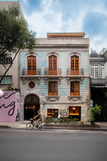 Man cycles past a historic building with ornate windows.