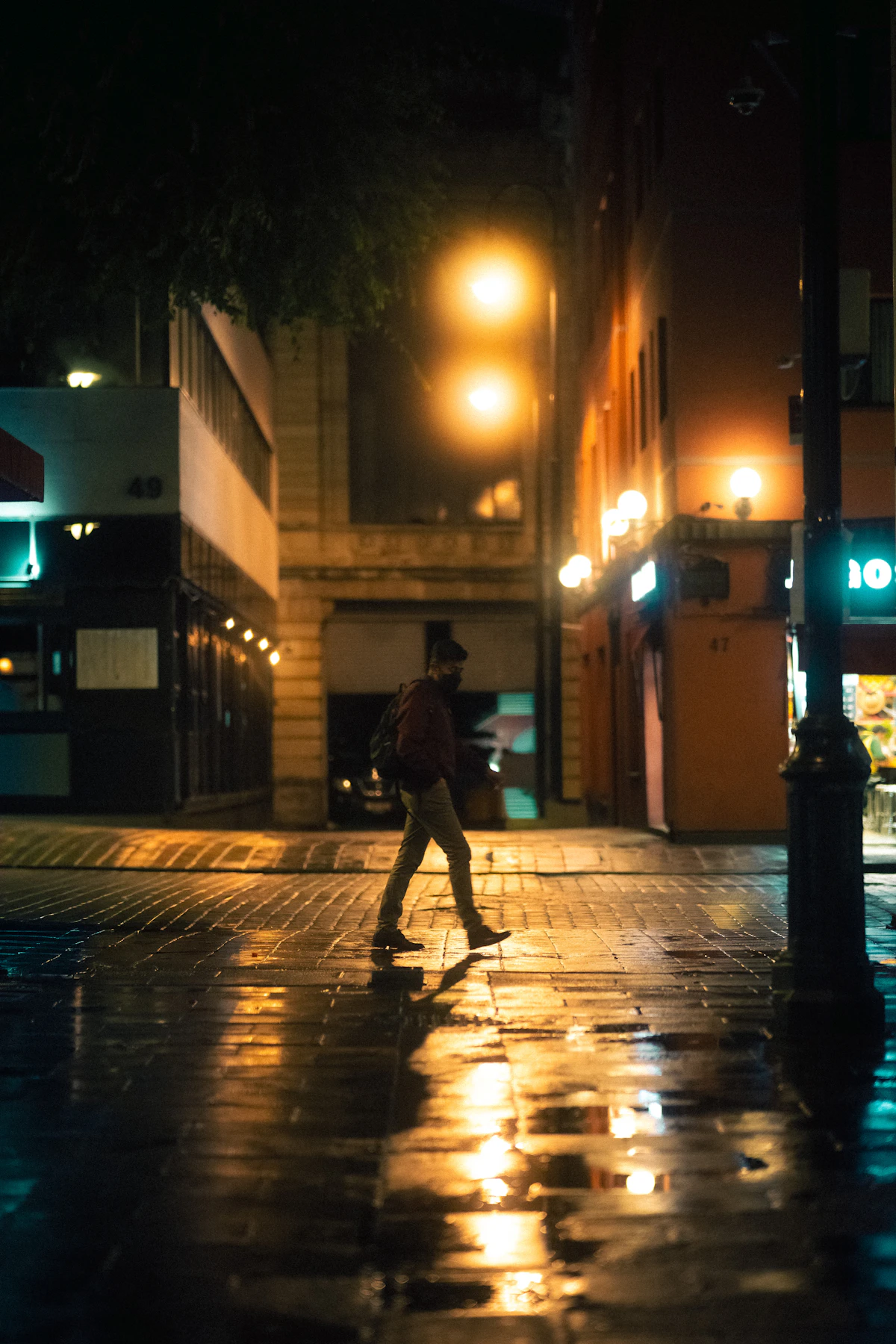 A person crossing a wet Mexico City street at night