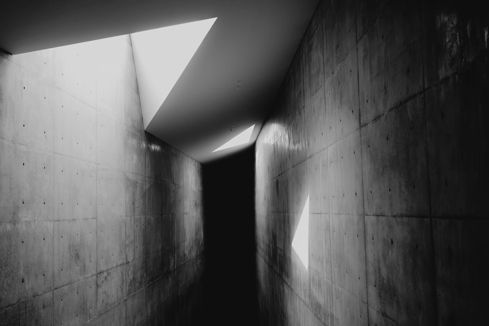 A concrete corridor with geometric light and shadow