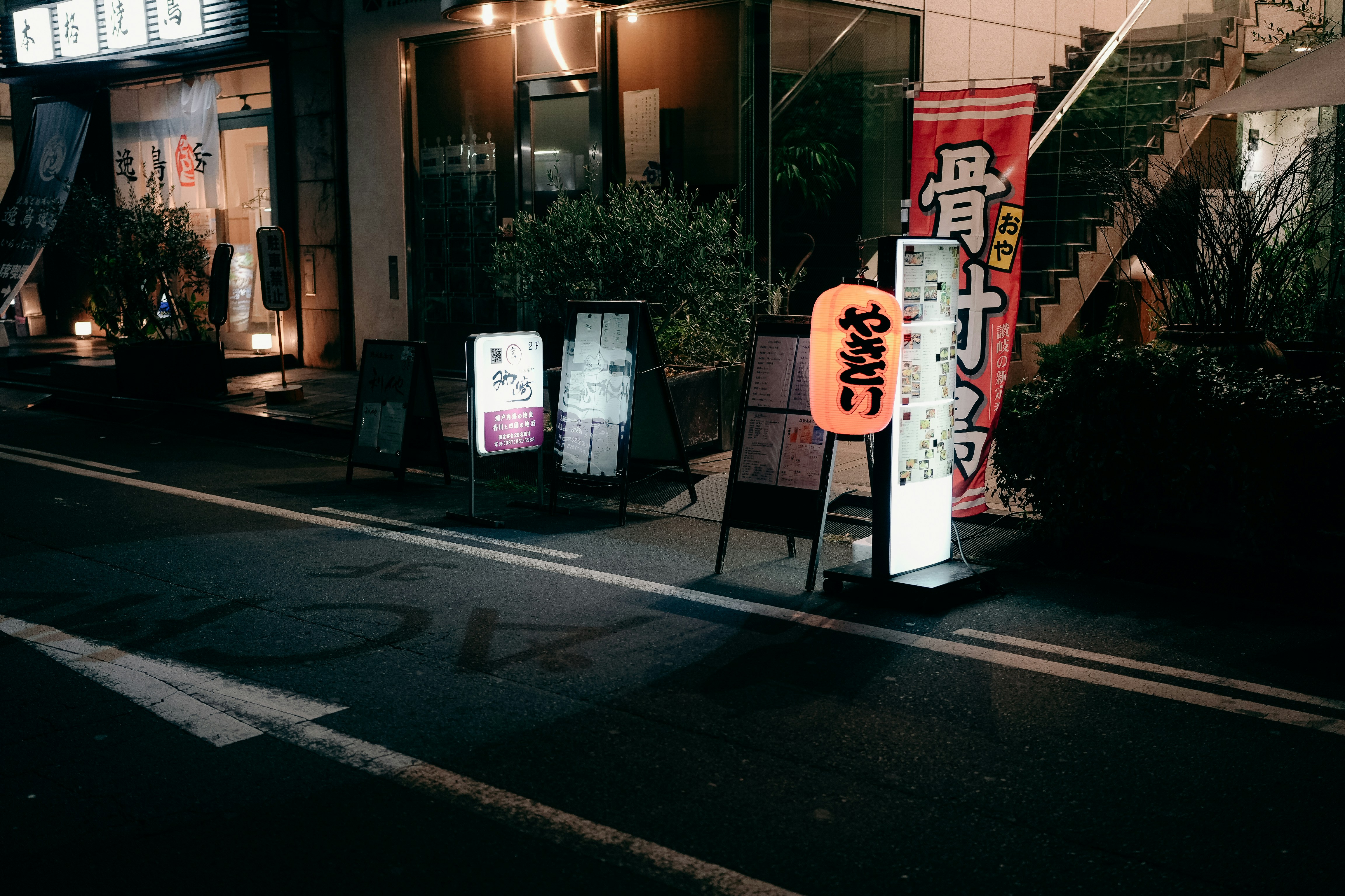 Tourist looking confused at a Japanese restaurant sign, night time