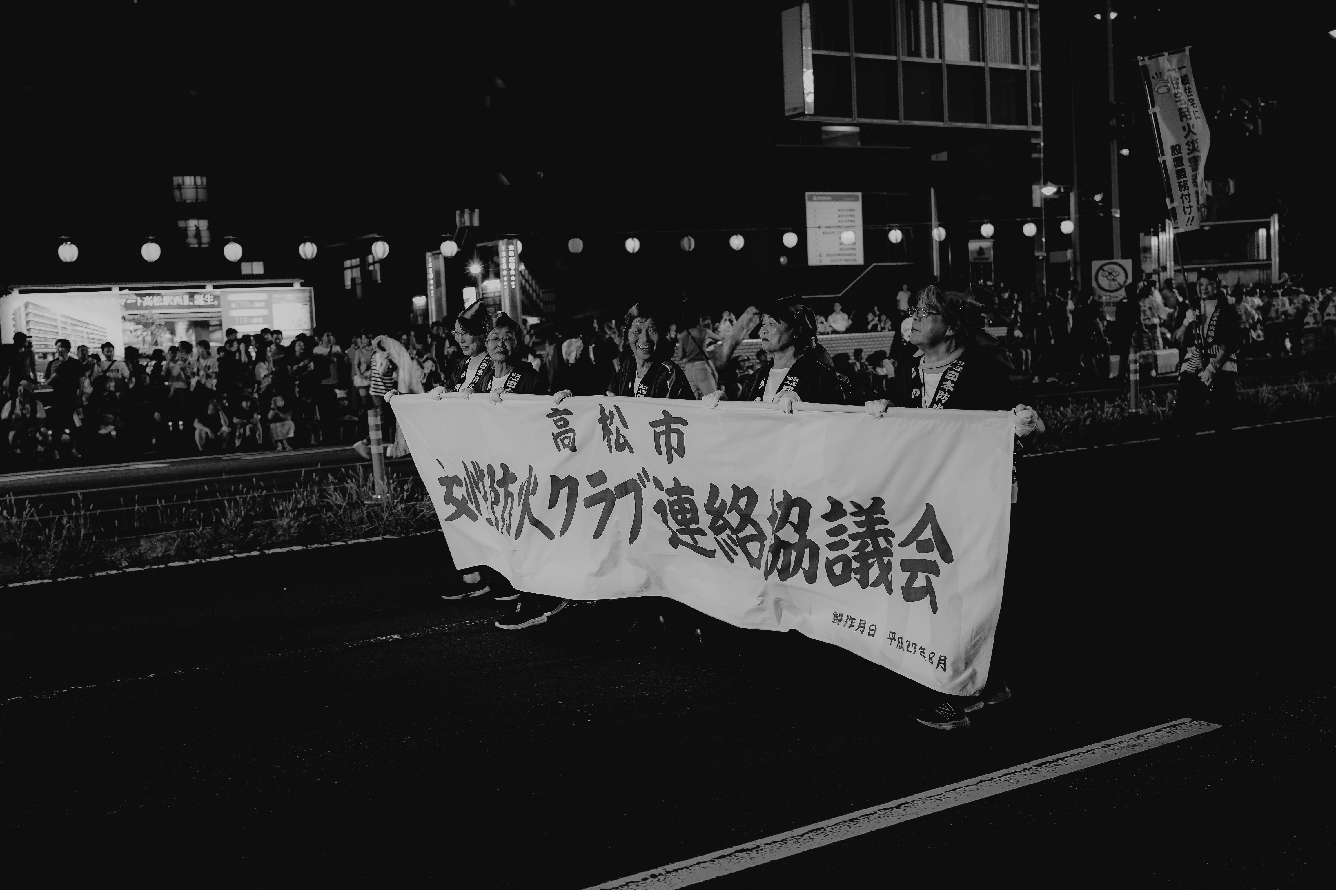 People carrying a banner in a nighttime street protest.
