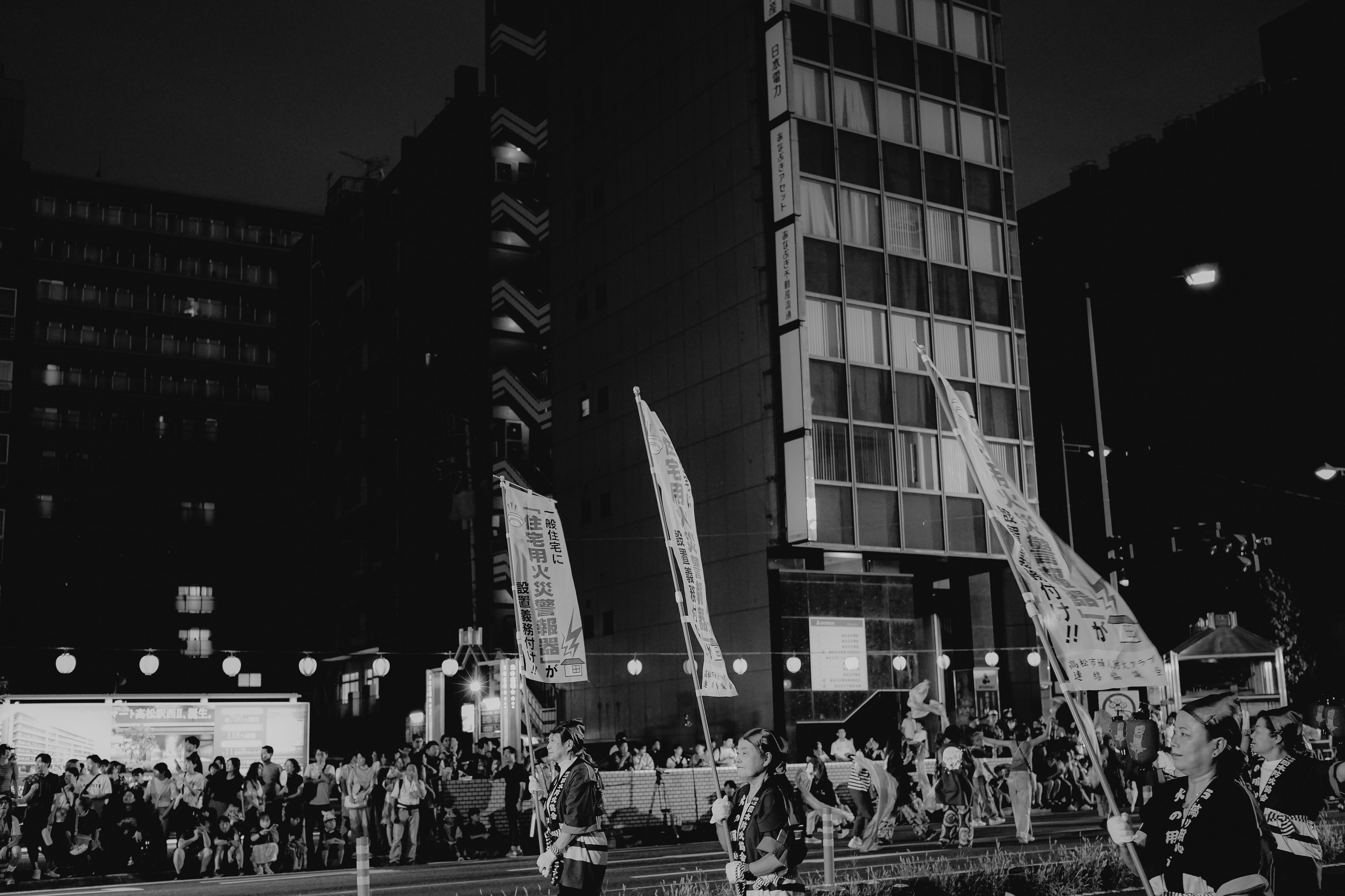 People gathered at night with flags in front of buildings
