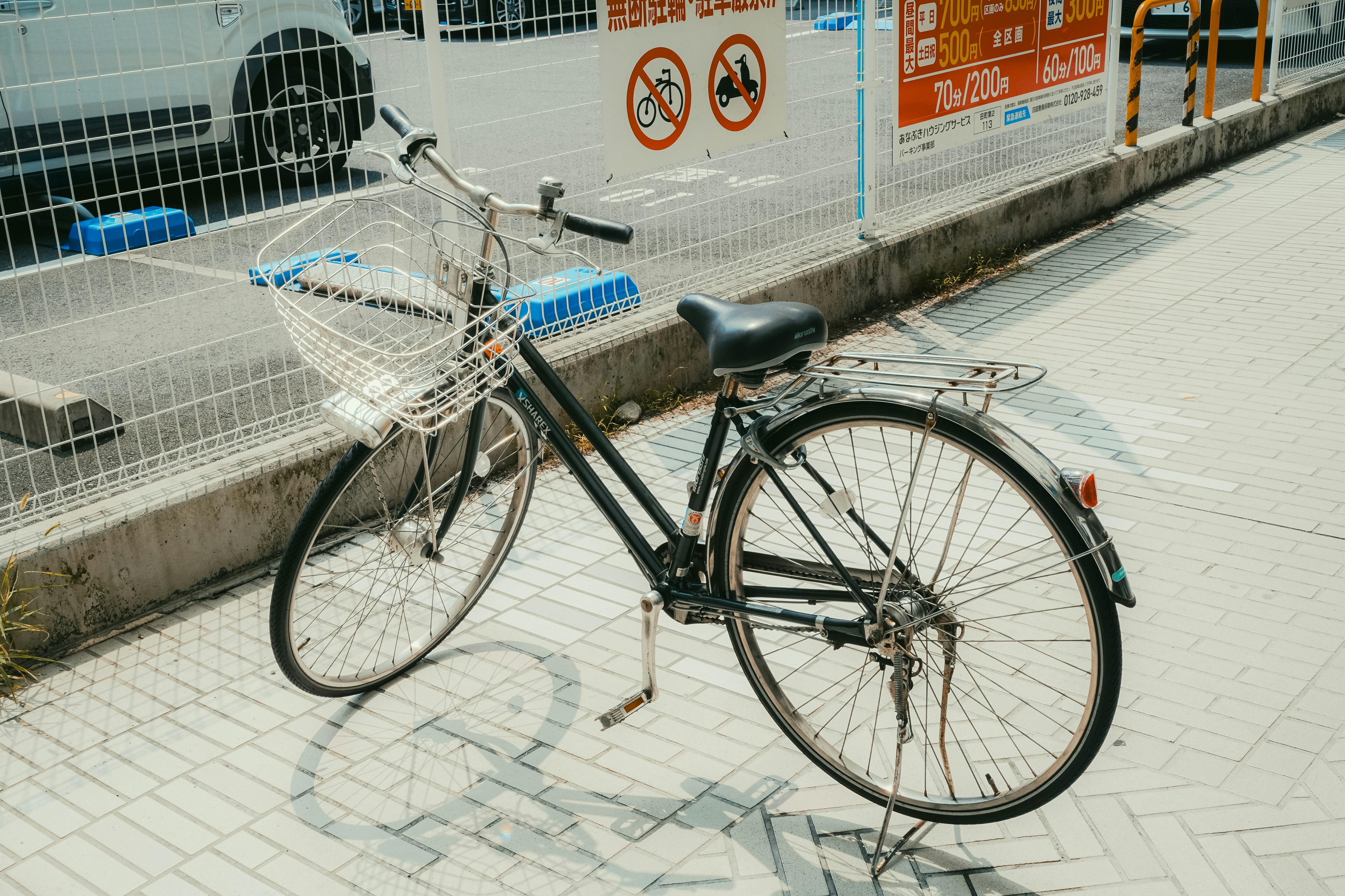 A bicycle with a basket parked on a sidewalk.