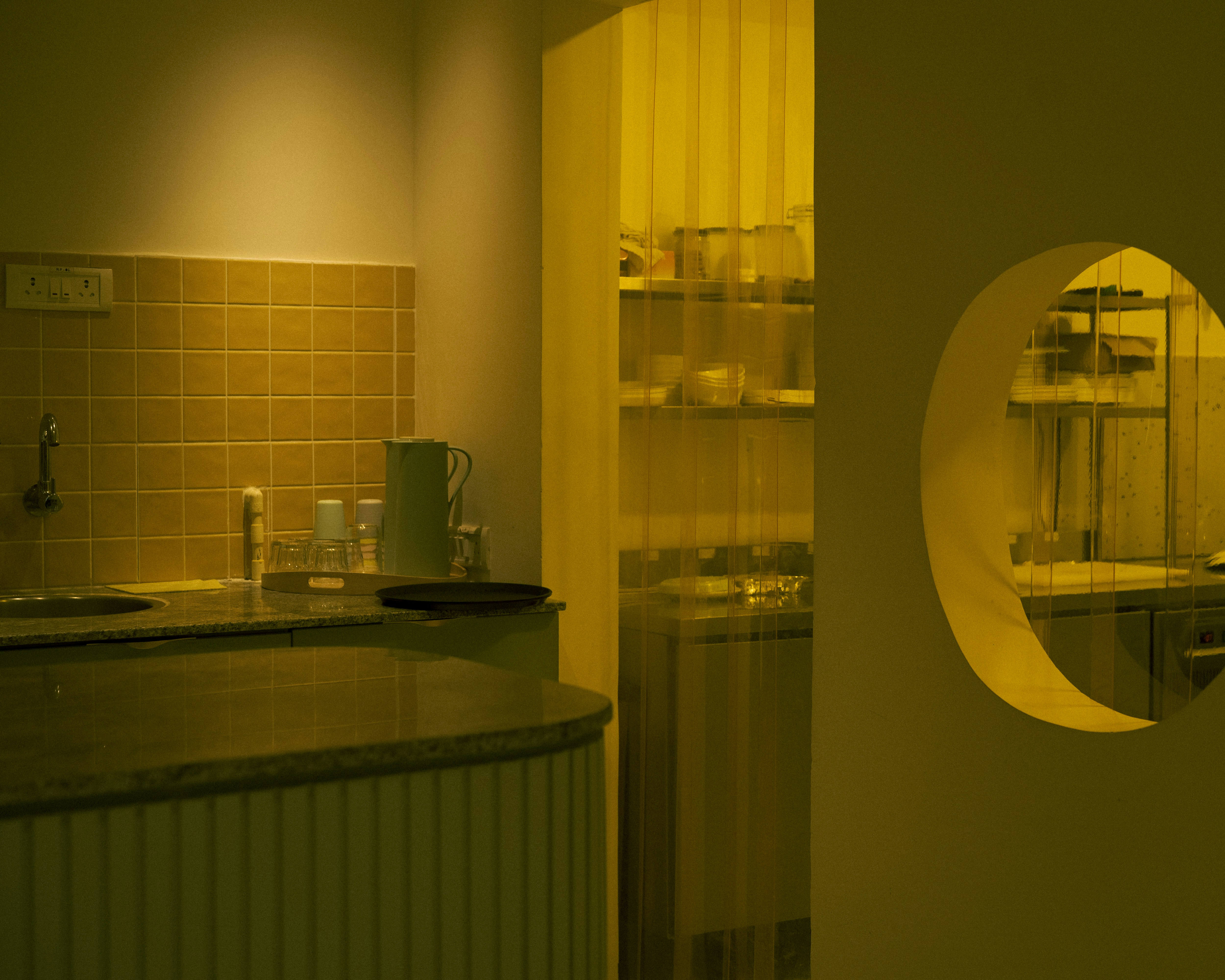 A modern kitchen with yellow lighting and shelves.