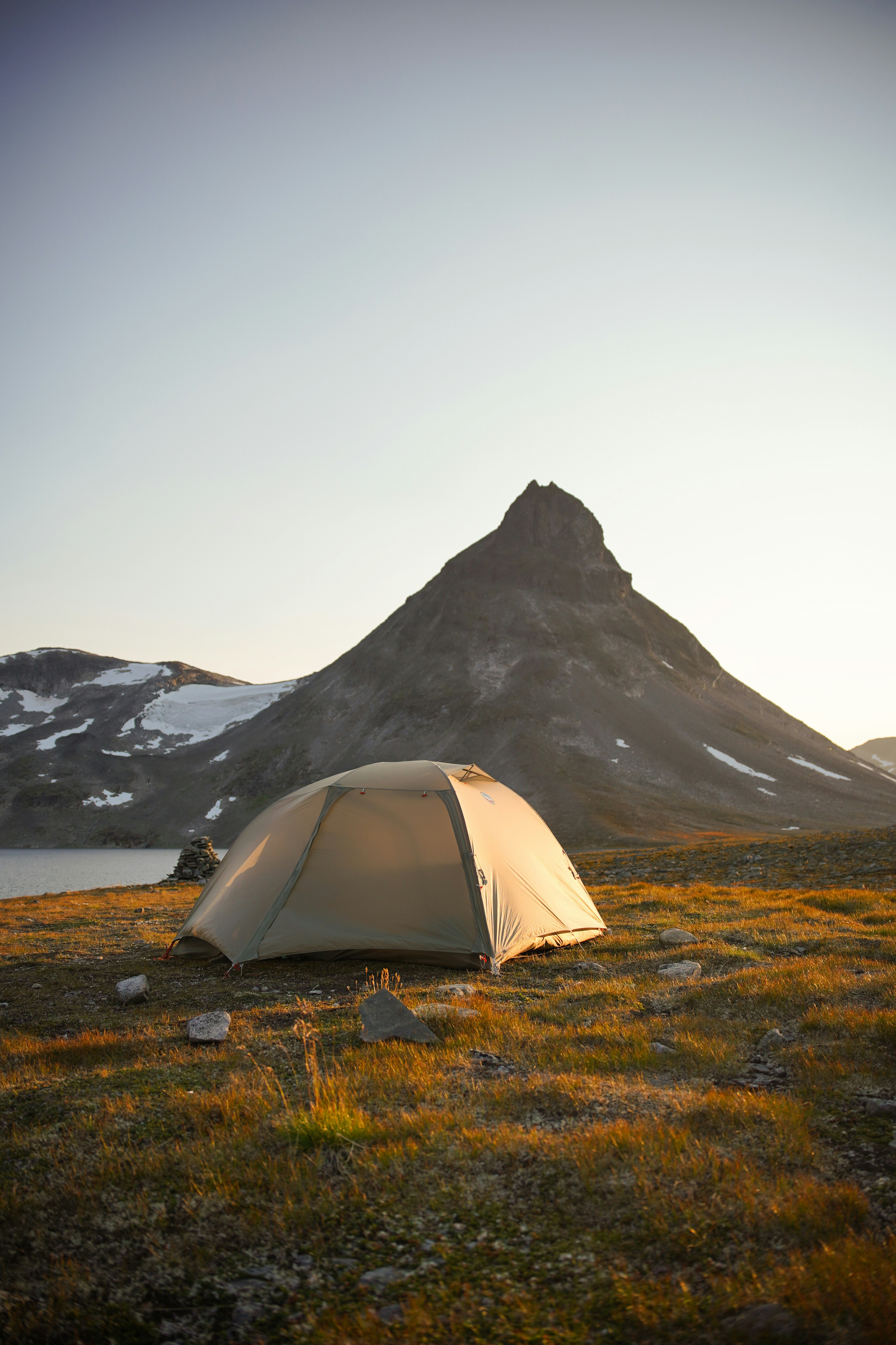 Zelt aufgeschlagen in einer bergigen Landschaft bei Sonnenaufgang.