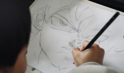 Child drawing anime character with pencil on paper