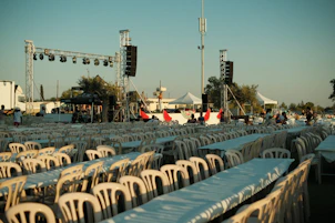 Rows of empty tables and chairs at an outdoor event.