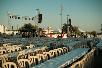 Rows of empty tables and chairs at an outdoor event.