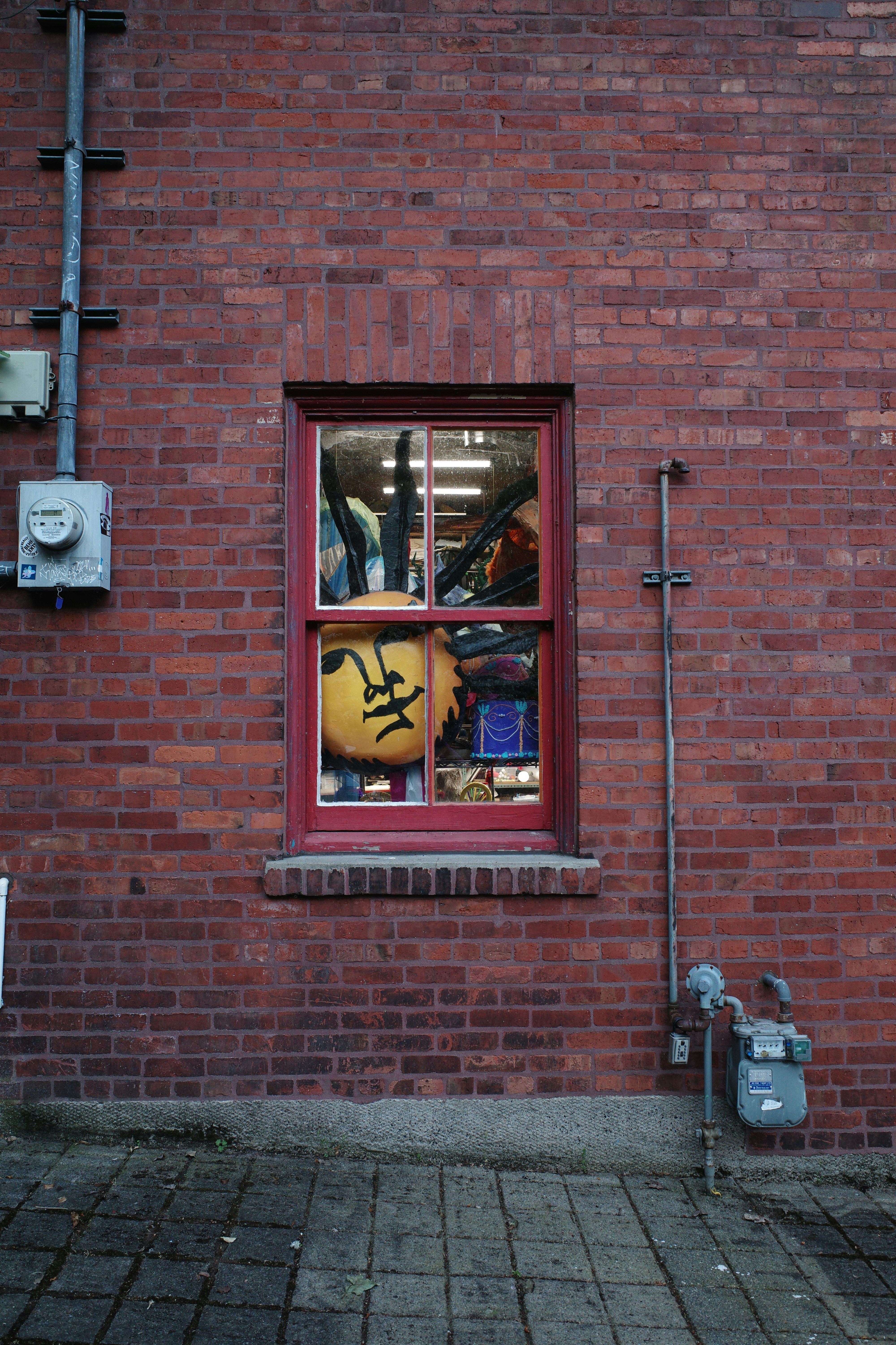 Red-framed window on brick wall with gas meter.