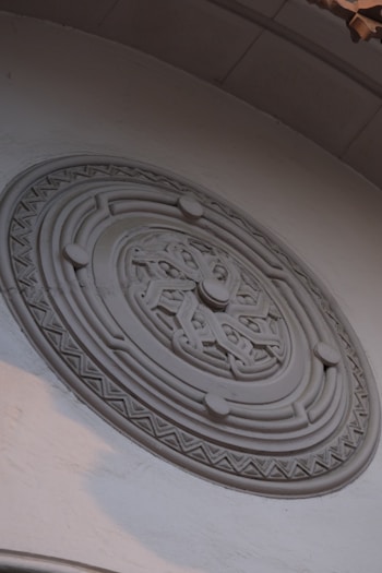 Ornate circular relief carving on a white wall.