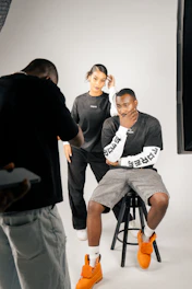 Photographer directs models during studio photoshoot.