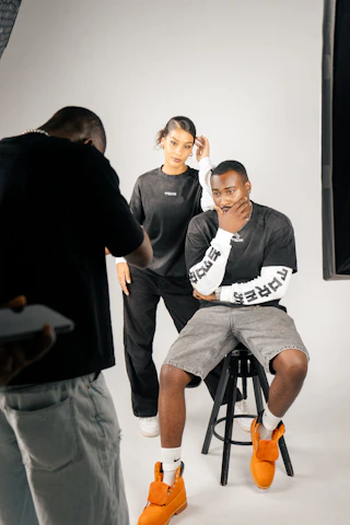 Photographer directs models during studio photoshoot.