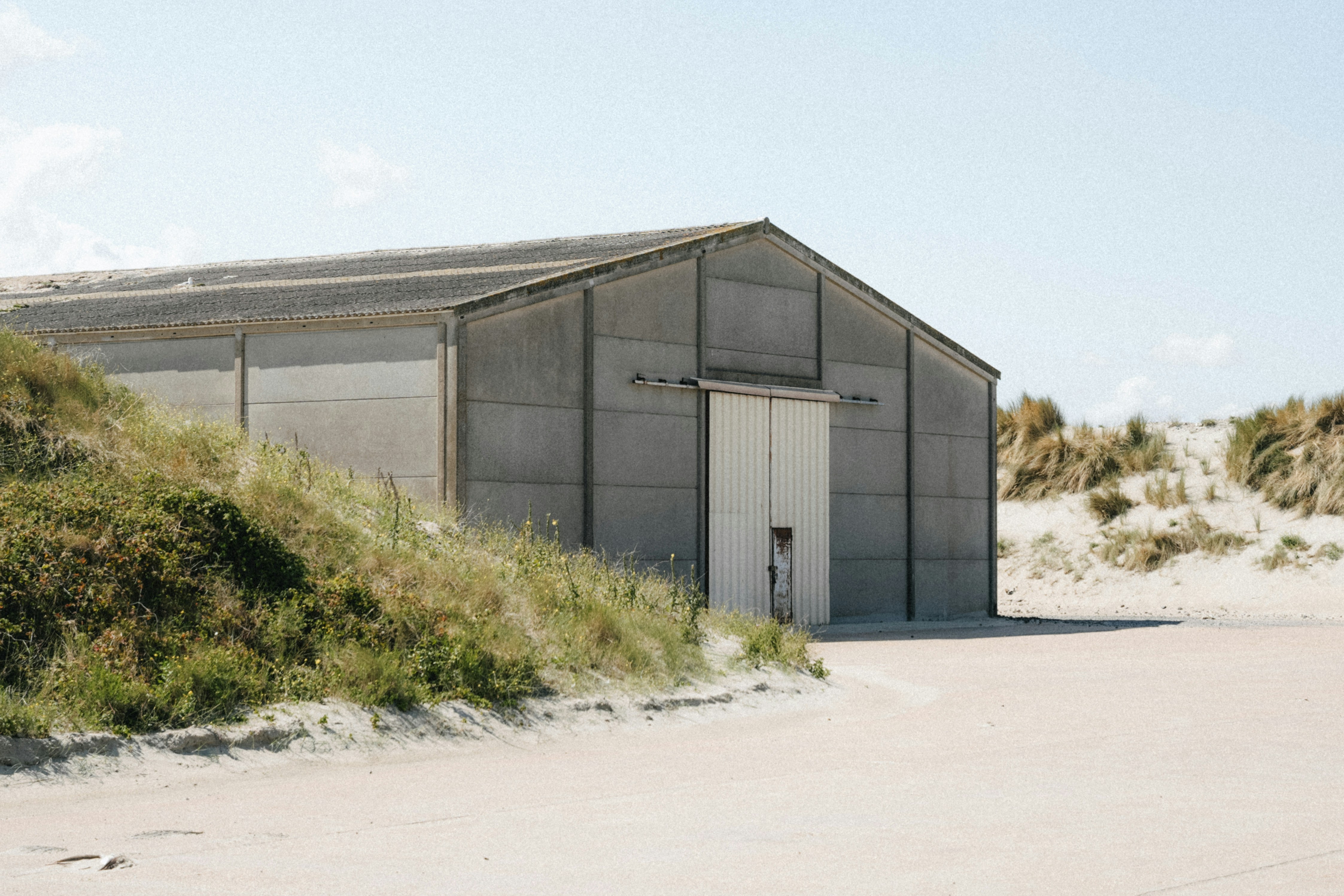 A large industrial building on a sandy landscape.