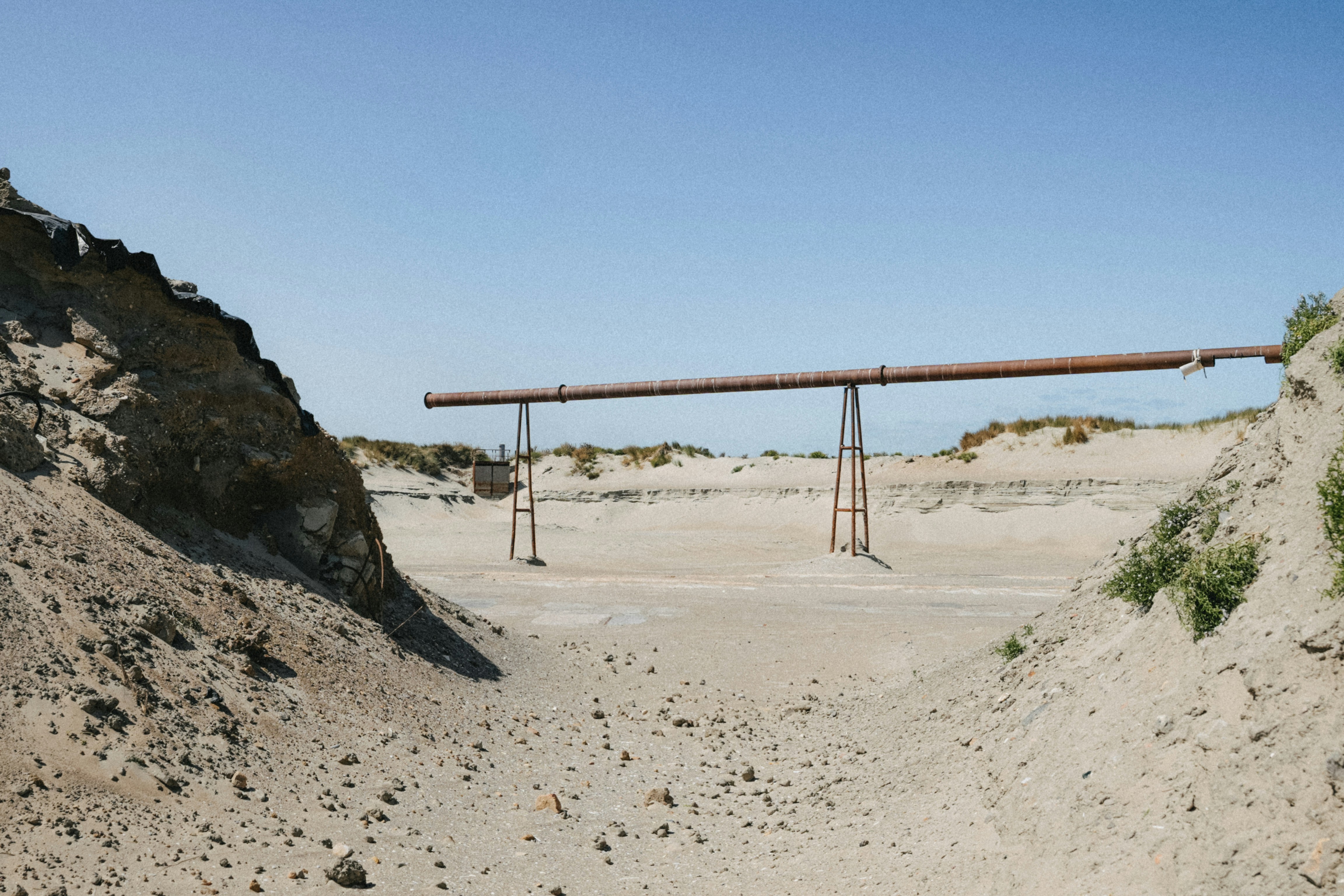 Long pipe crosses arid landscape under clear blue sky