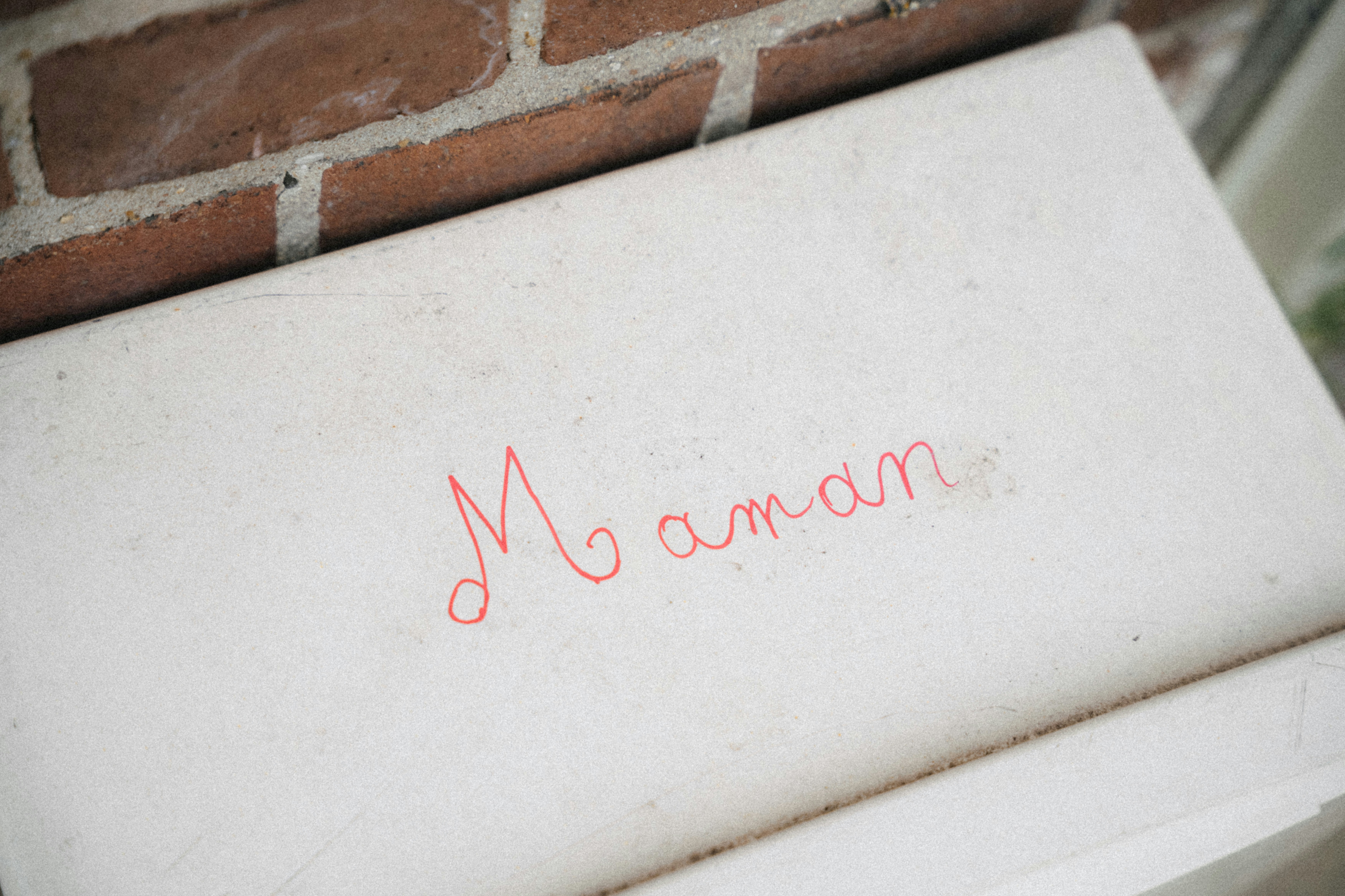 The word maman written in red on a white surface.