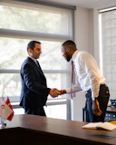 Two businessmen shaking hands across a desk.