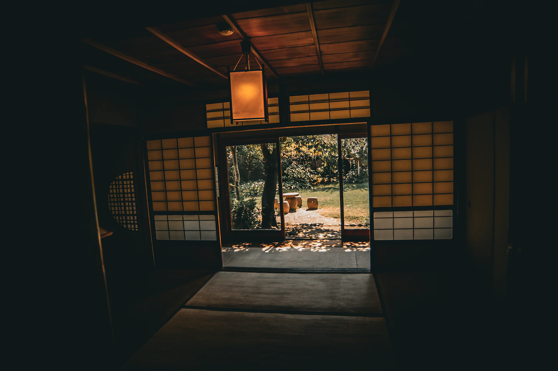 Dark ryokan room with a paper lantern and shoji open onto a garden
