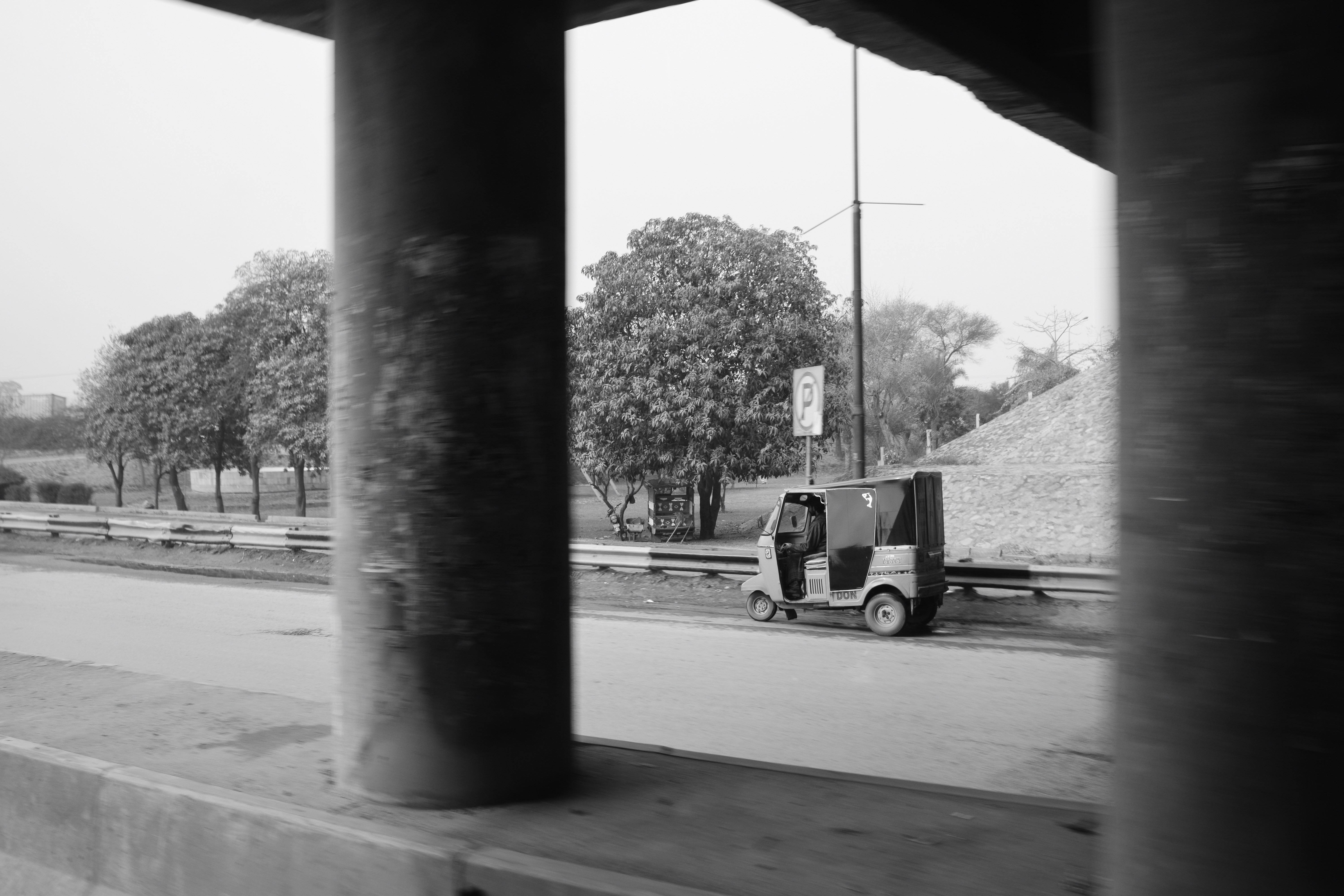 Auto rickshaw parked beside a road with trees
