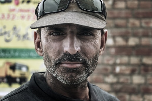 Man with a cap and sunglasses on his face beard