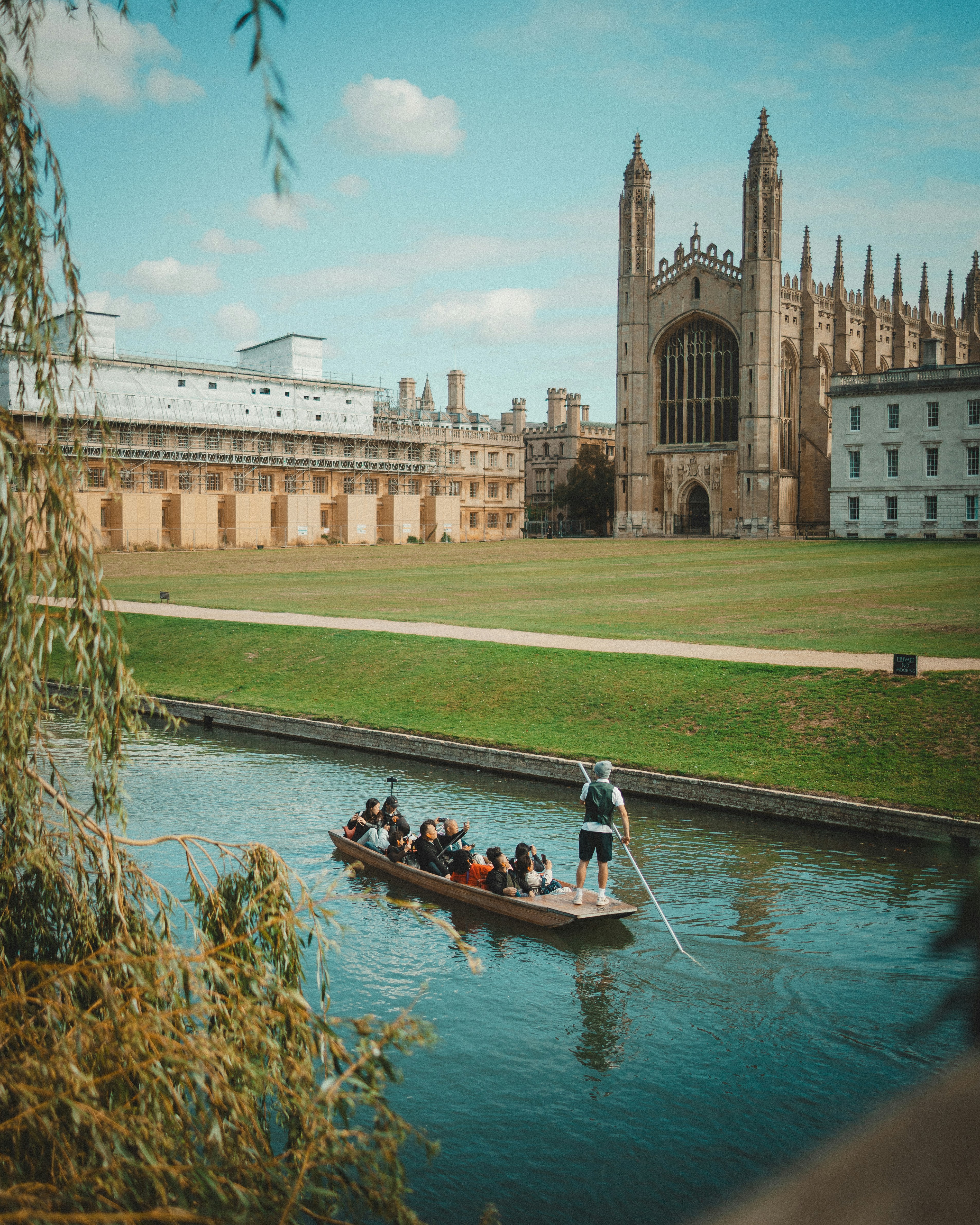 People punting on a river near a historic building