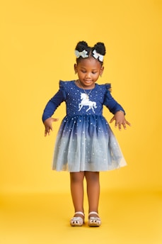 Young girl in a blue unicorn dress on yellow background