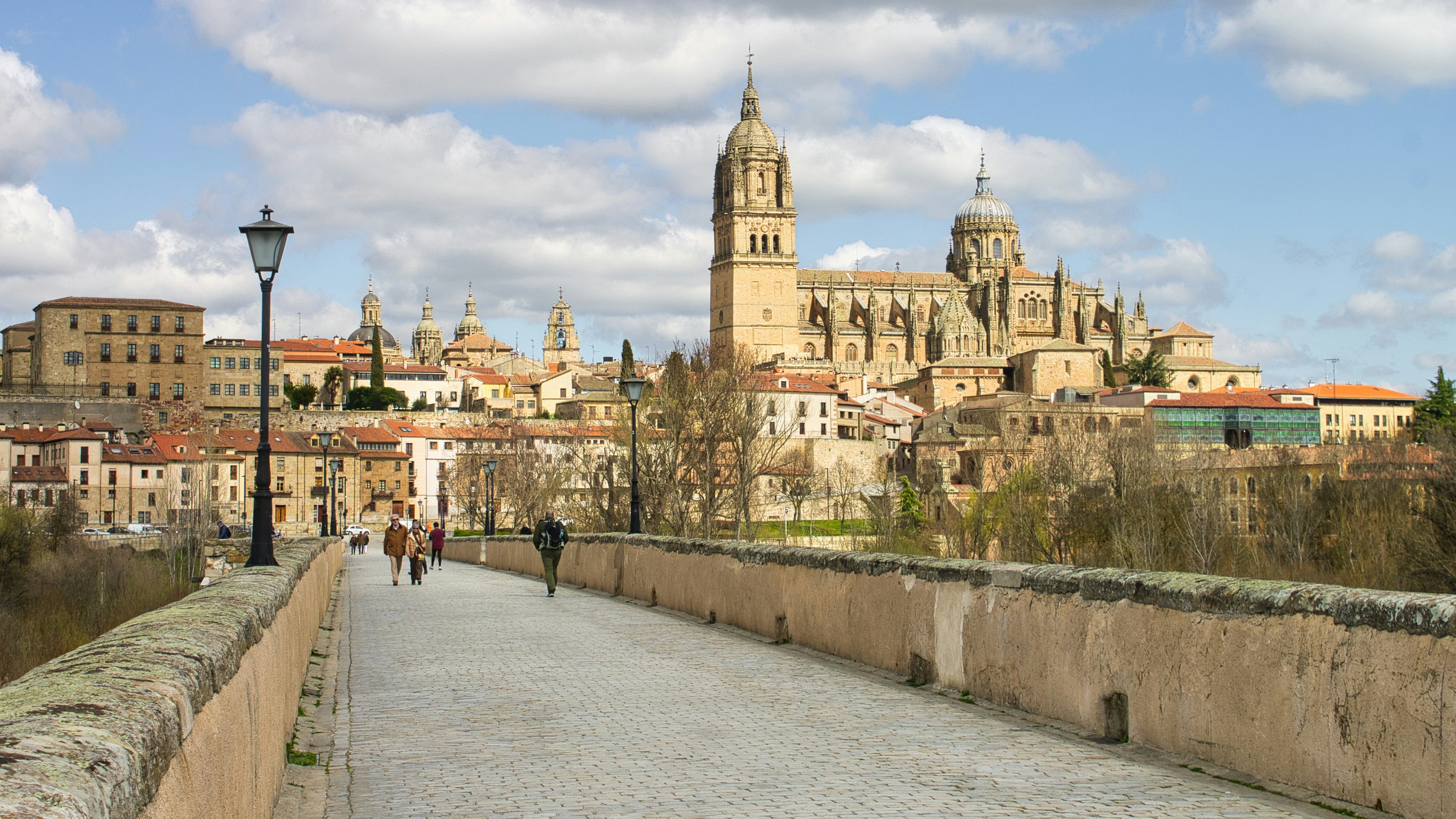 Historic stone bridge leads to european city skyline.