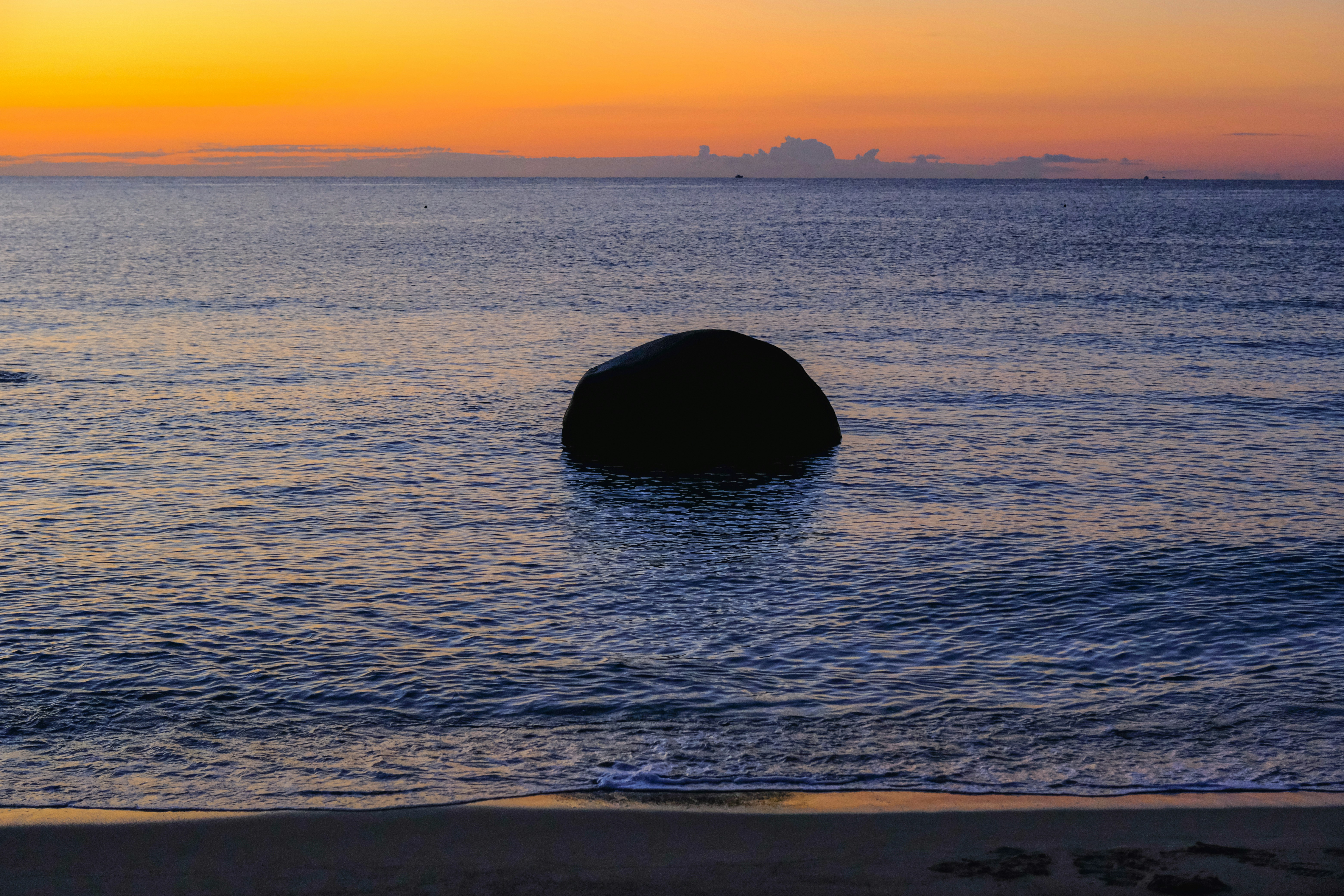 Large rock in the ocean at sunset