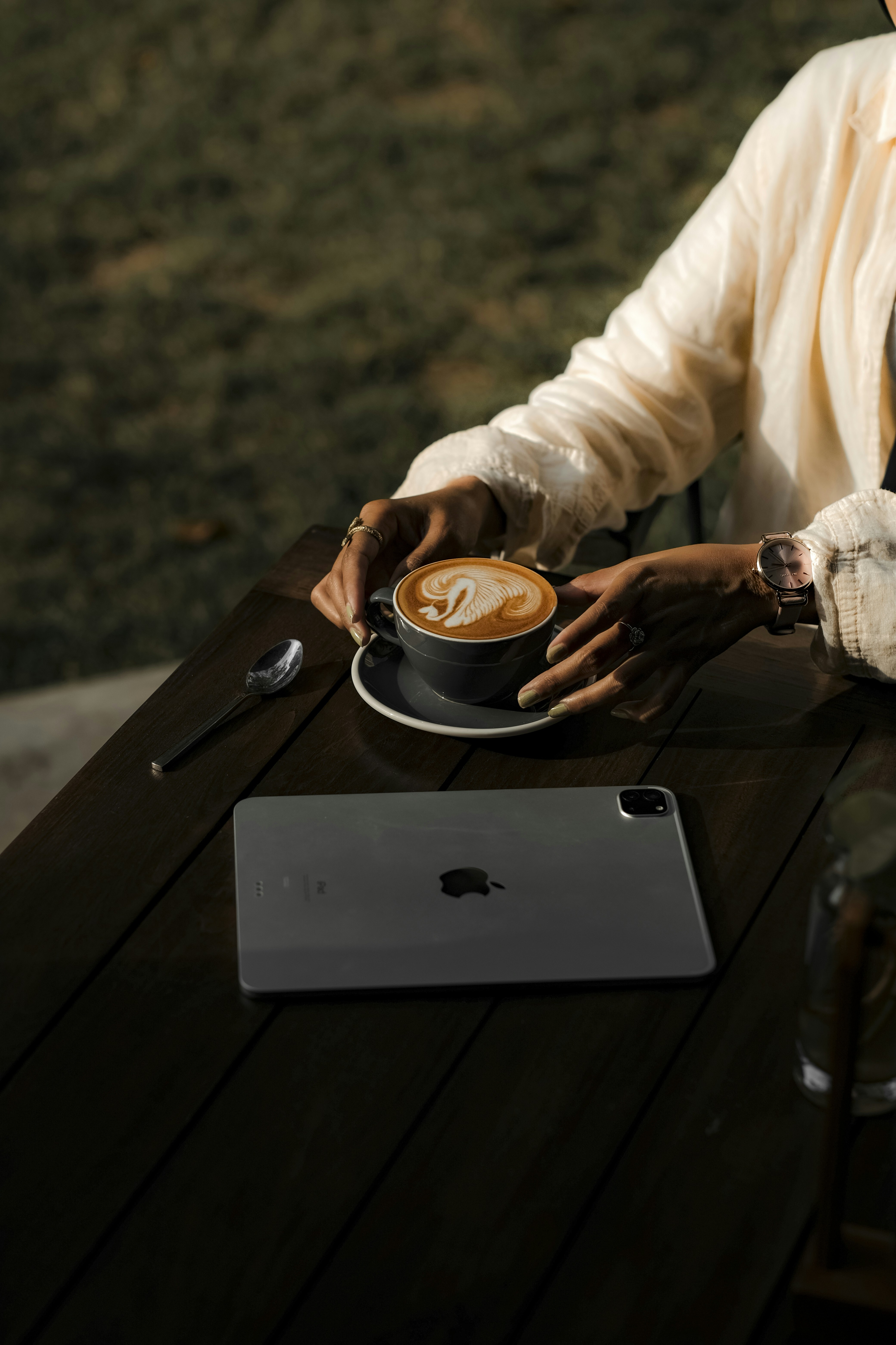 Person holding a latte with latte art at a table.