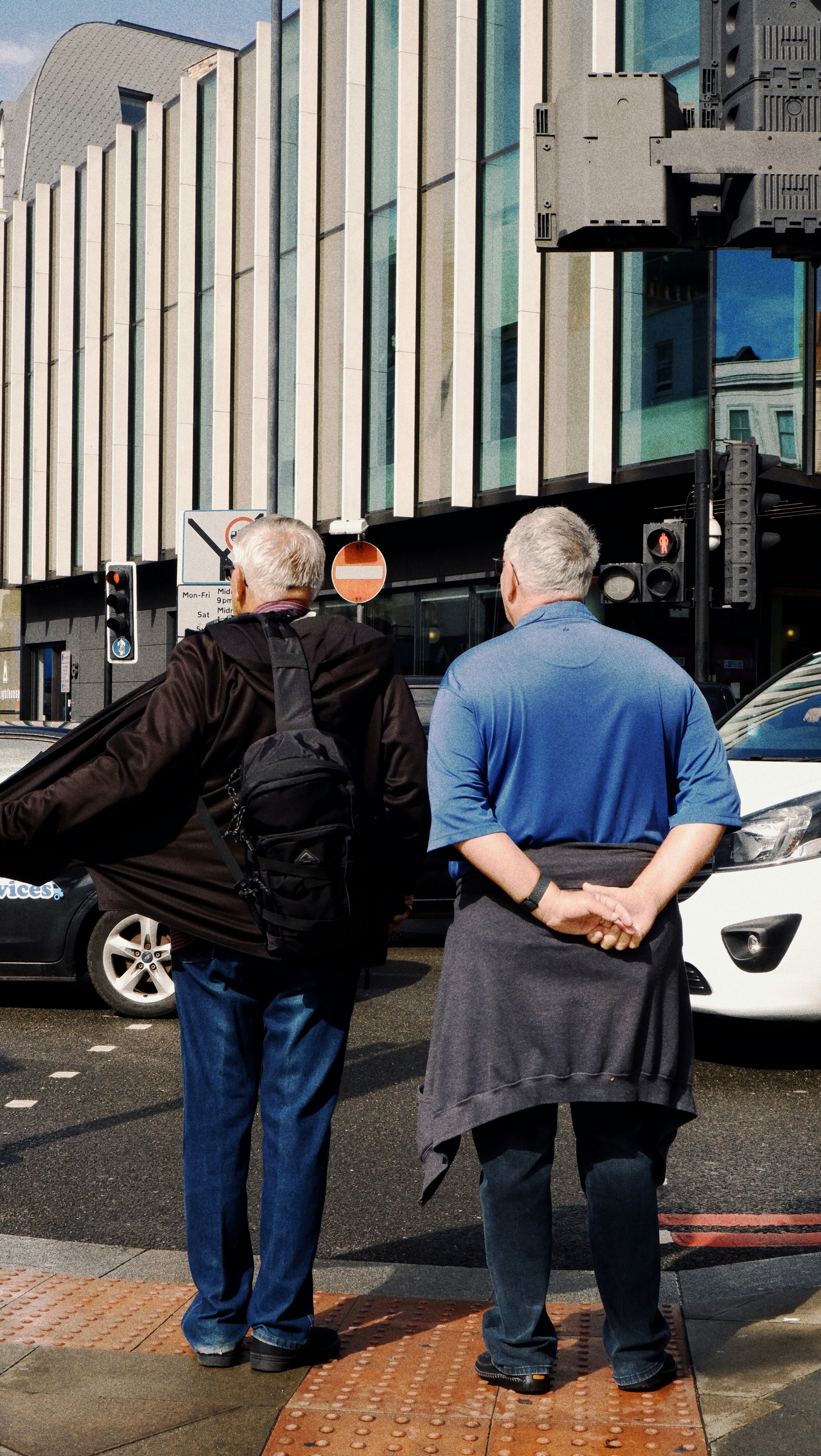 Two men stand on a city street corner.