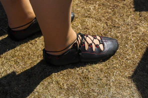 Close-up of feet wearing black lace-up shoes on grass.